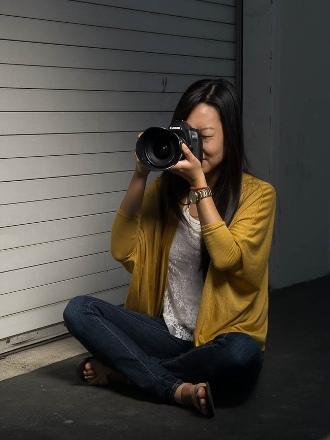 Incorrect seated camera position with legs extended or crossed providing no elbow support or stable bracing for the camera