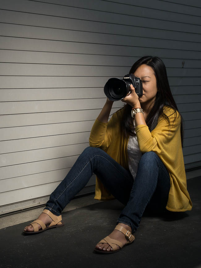 Correct seated camera position with feet flat on ground knees raised and elbows braced on knees creating a stable three-point platform