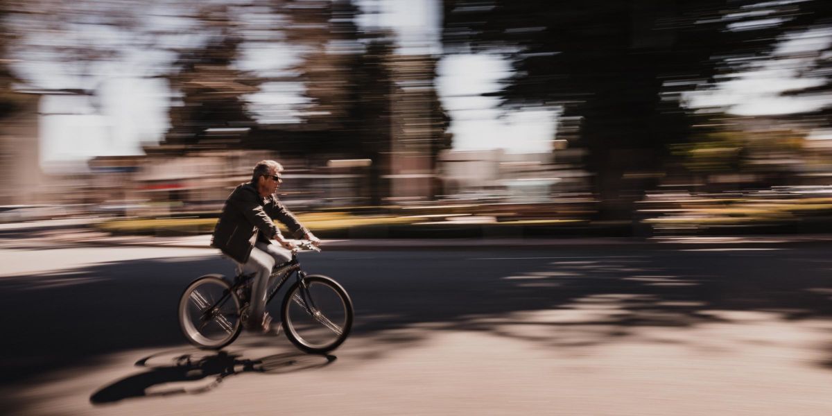 Panning photography example of a cyclist with motion blurred background showing how panning conveys speed and movement at a slow shutter speed