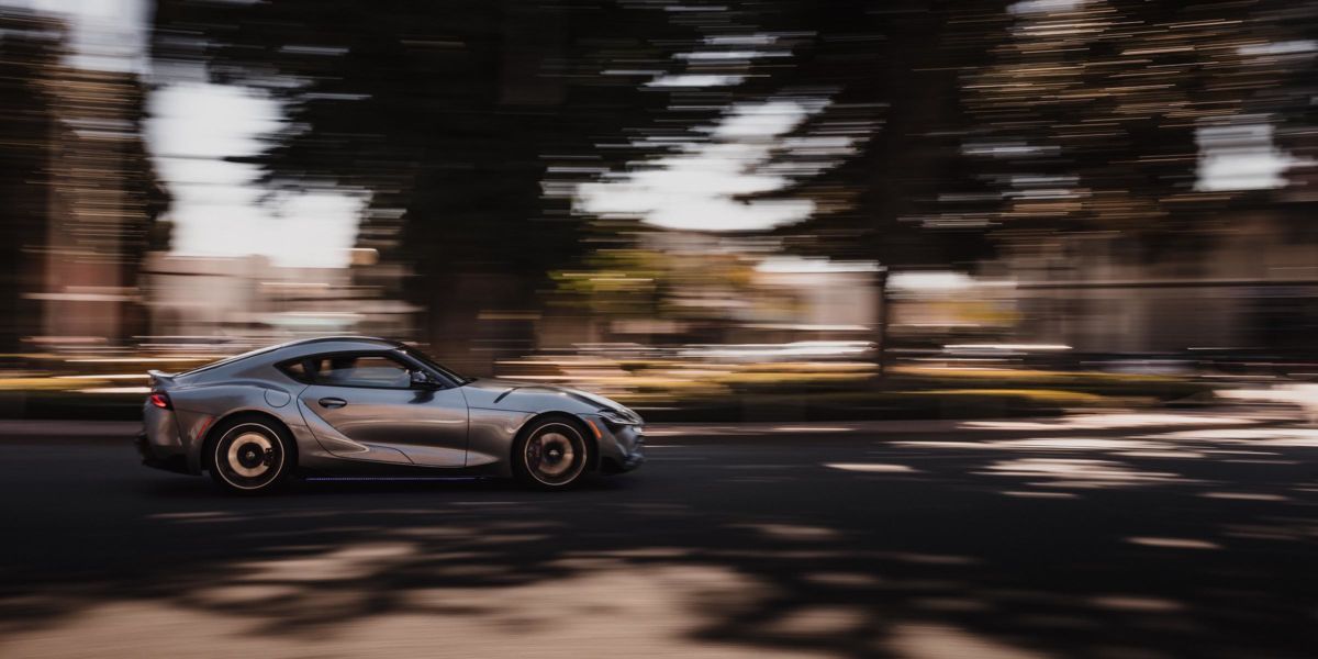 Panning photography example of a sports car with colorful streaked background showing the effect of smooth camera tracking at a slow shutter speed