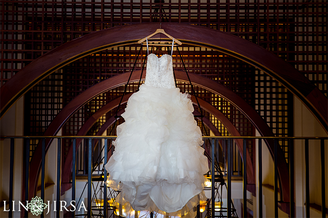 Wedding dress detail shot hanging near a large window with soft natural light illuminating the fabric and lace details for bridal photography