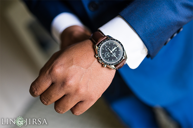 Groom's watch detail shot resting on a folded tie with soft window light revealing the dial and strap details for groom prep photography